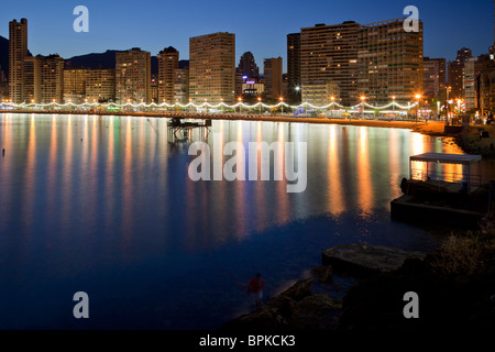 Benidorm`s attractive north end corner Levante beach at dusk, with its buildings and lighted promenade reflecting in the sea. Stock Photo